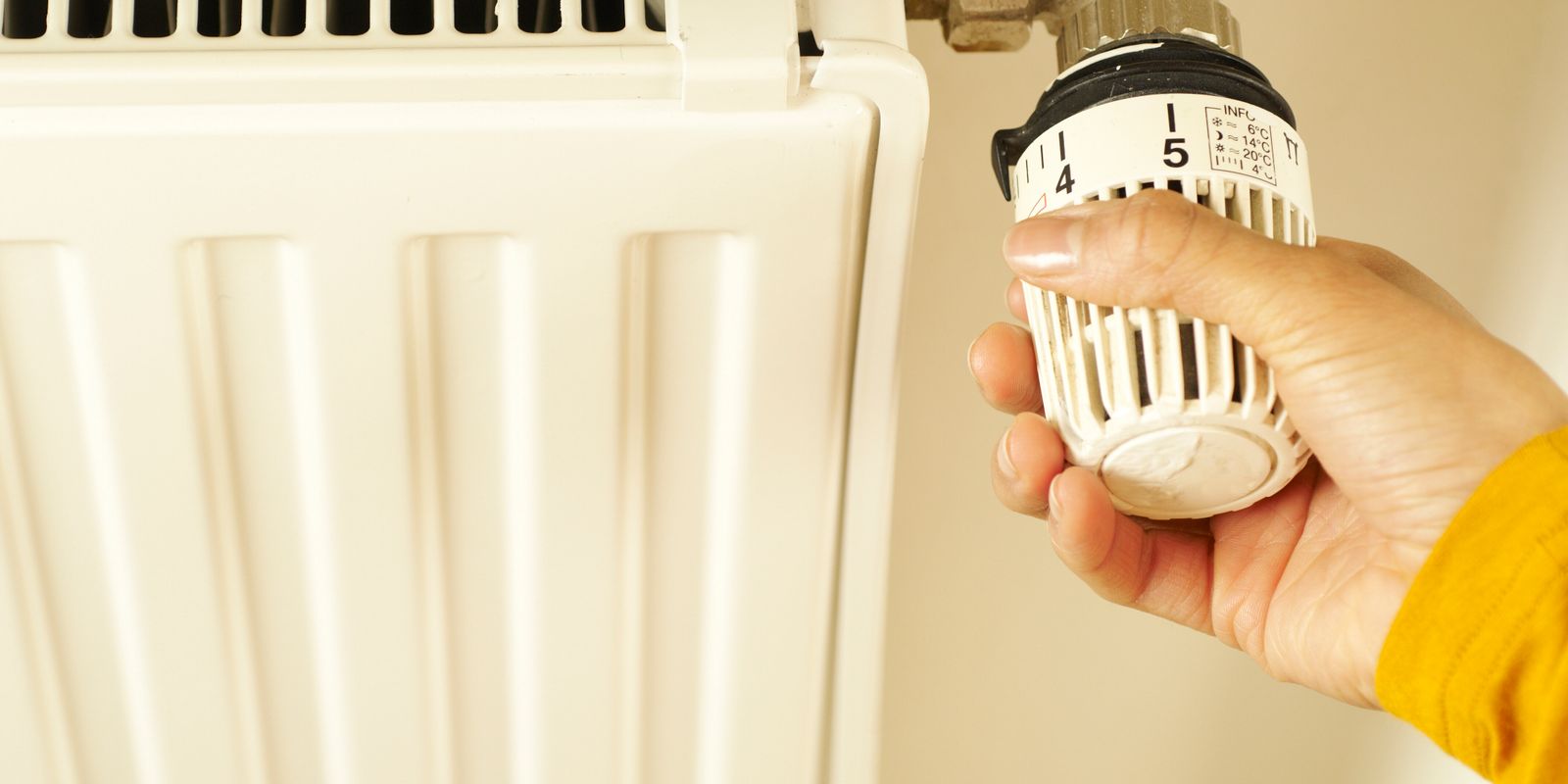 Main r&eacute;glant le robinet thermostatique d&rsquo;un radiateur