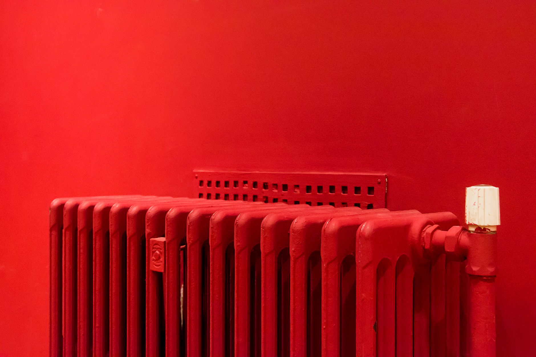Radiateur rouge posé contre un mur assorti