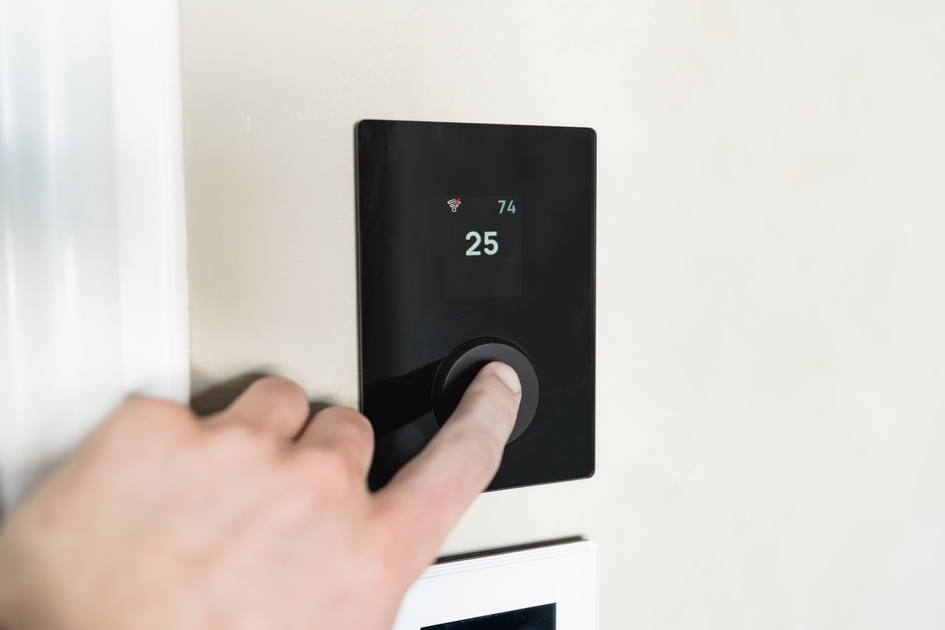 Main sur un thermostat connecté mural